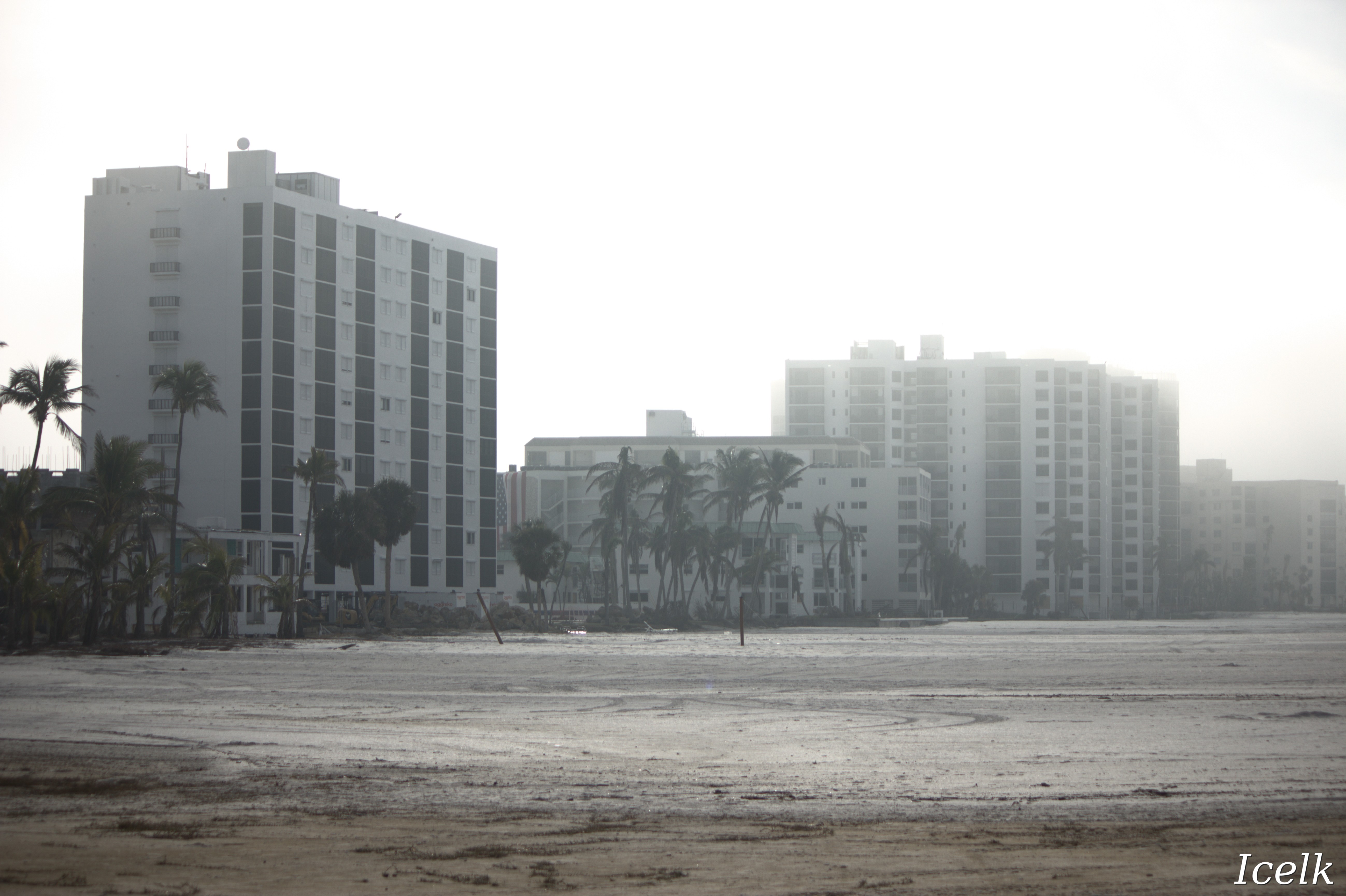 foggy beach with tall rectangular resort buildings in the background