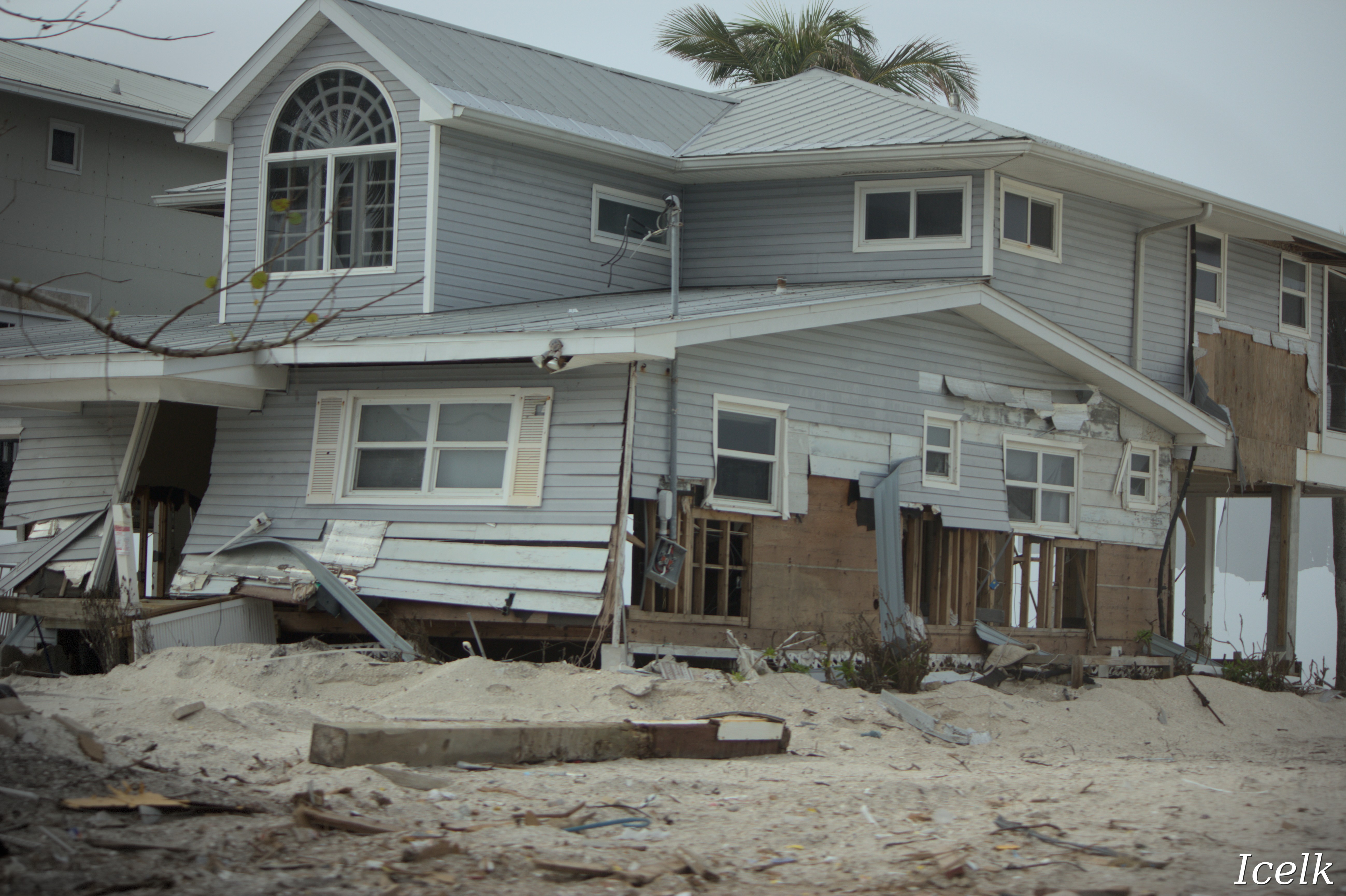 house with ground-level panelling and structural damage